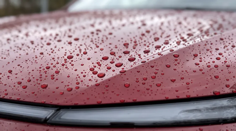 Water beading on the ceramic coated red hood of a Tesla Model Y