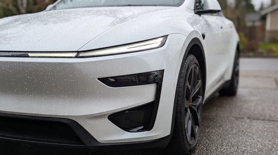 Water beading on the front bumper of a white Tesla Model Y Performance